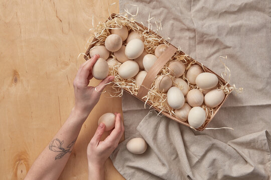 Basket with wooden eggs taken by woman's hands.