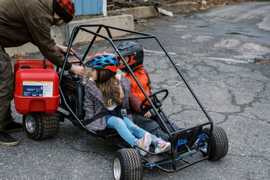 Father filling up children's go kart with gasoline from a tank