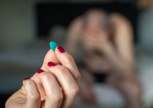 Woman hand holding a blue pill on blurred background, concept of male sexual health and erectile dysfunction treatment