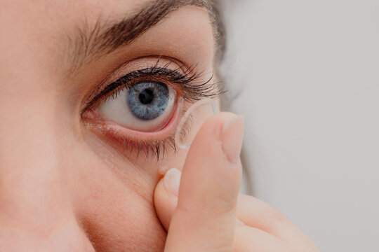 Crop woman putting on contact lens