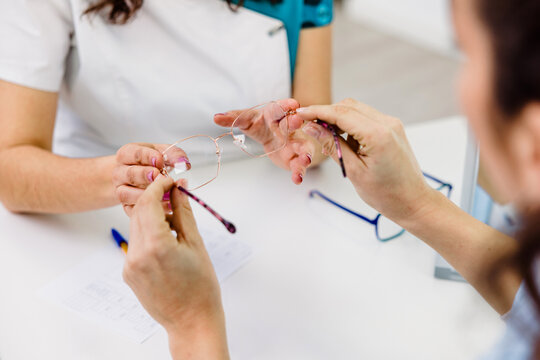 Crop oculist and client selecting glasses