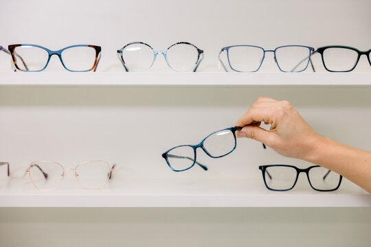 Anonymous woman choosing glasses in optic shop