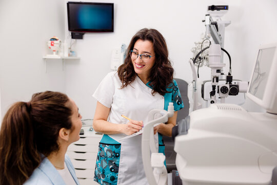 Smiling oculist talking to patient in clinic