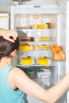 The thoughtful girl opened the refrigerator filled only with cakes