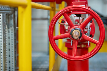 Fototapeta na wymiar Red fire water valve on the piping system of the industrial firefighting system in the technological complex. Components of automatic fire extinguishing system. 