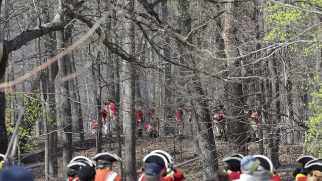Tower Park, Lexington, MA, USA - April 15, 2023: Men dressed as 18th century British soldiers (redcoats) reenact one of the first battles of the American revolution as part of annual celebration.