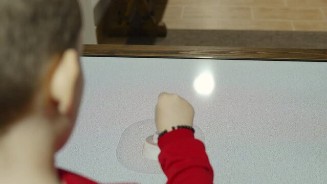 Elementary boy uses proximity screen in museum, close-up. Child moves hand, opens images of ancient exhibits, view over the shoulder. Use of use of augmented reality technologies in teaching children.