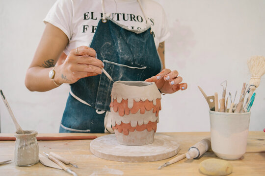A faceless woman creating a unique and different piece of ceramics
