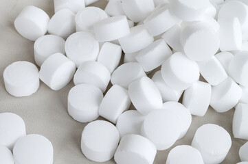 White round large pills are scattered on the table. Salt capsules isolated top view