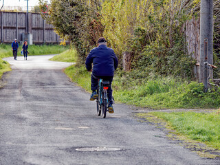 Old senior man riding a bicycle, biking on the rural countryside roads