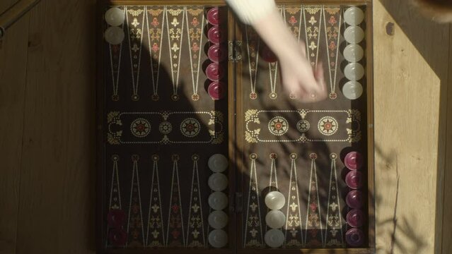 woman wins the throw, women hands roll a 6 and a 1 in backgammon in 4k, top shot of backgammon board, starting a new game.