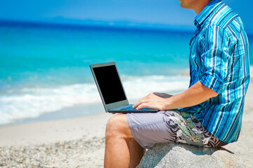 A Happy man guy with laptop near the seashore weekend travel