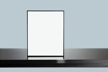 Wooden black frame mockup on a wooden desk with a Blue wall Background