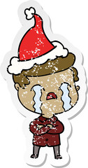 distressed sticker cartoon of a man crying wearing santa hat