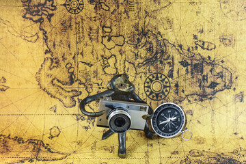 Classic round compass and souvenir figurine with camera on background of old vintage map of world