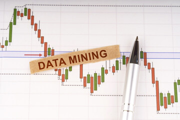 On the chart of business quotes lies a pen and torn paper with the inscription - DATA MINING