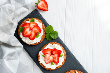 Healthy sandwich with strawberry and cream cheese on slate board. Tasty breakfast. Clean eating, diet or easy recipe of vegetarian sandwich for vegan menu. Flat lay.