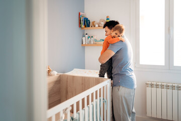 Father hugging a child next to a cradle