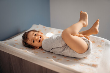 Smiling baby boy lying on changing table