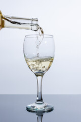 Pouring white wine from a bottle into a glass