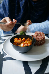 cooked red rice , vegetable salad and fish curry in a bowl on table 