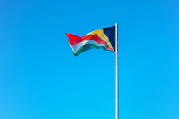 Waving colourful flag of Seychelles on a blue sky background