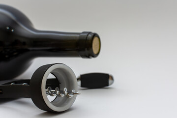 Black corkscrew and unopened bottle of wine