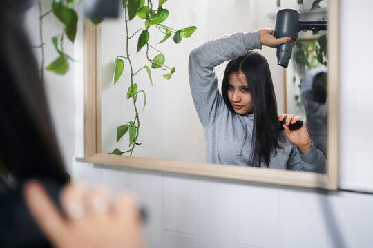 Woman drying wet hair near mirror