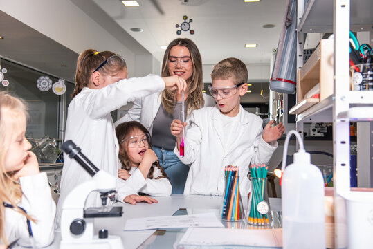 Diverse schoolchildren with teacher work together on science project