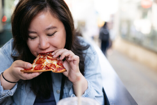 Girl eating pizza on patio downtown.