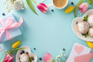 Say thank you to your mom this Mother's Day. Top view flat lay of cupcakes, gifts, postcard, coffee, and tulips on a pastel blue background. Use the empty space for a message or advertisement