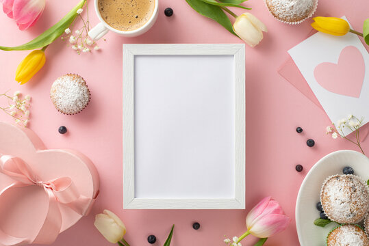 Make your Mom feel special on Mother's Day with a beautiful top view flat lay of cupcakes, presents, coffee cup, and tulips arranged on a pastel pink background with an empty frame for special message
