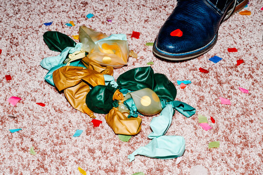 deflated balloons, confetti and shoe on the carpet