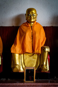 A golden buddha statue wearing an orange frock at a temple in Thailand