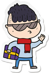 sticker of a cartoon boy wearing sunglasses carrying xmas gift