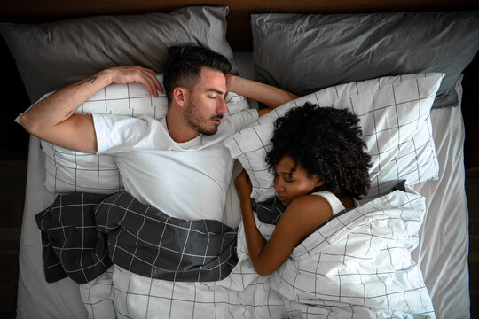 Pregnant couple sleeping in bed 