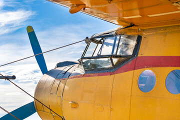 Cockpit of an old yellow-painted airplane with the blue sky in the background