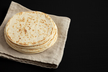 Stack of Whole Wheat Flour Tortillas on a black background, side view. Space for text.