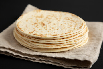 Stack of Whole Wheat Flour Tortillas on a black background, side view. Close-up.