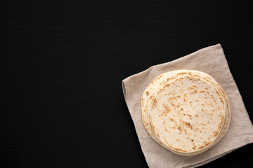 Stack of Whole Wheat Flour Tortillas on a black background, top view. Flat lay, overhead, from above. Copy space.