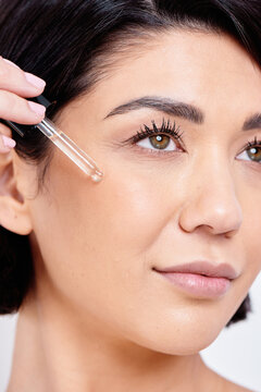 Macro beauty portrait of female model applying serum to cheekbone