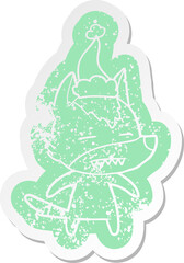 Obraz premium cartoon distressed sticker of a wolf showing teeth wearing santa hat