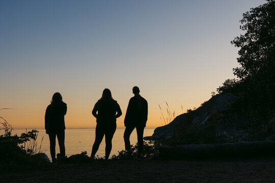 Three friends hanging out together at sunset in nature.