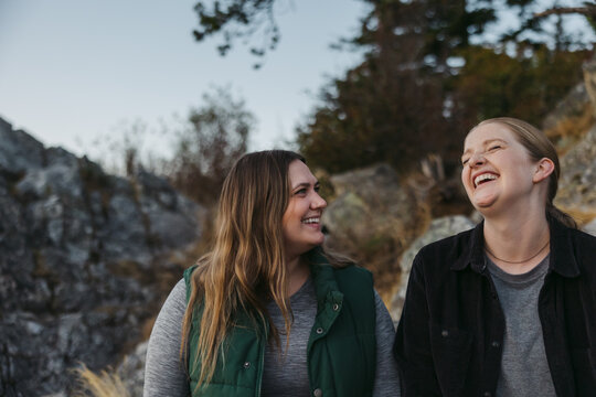 Two friends laughing together outside in nature.