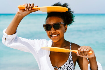 Cheerful black woman with frescobol paddles