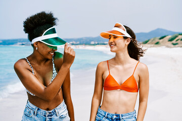 Obraz premium Female friends on beach in sun visors