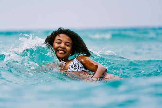 Cheerful black woman swimming in sea
