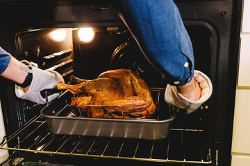 Unrecognizable man taking out ready crispy turkey from the oven