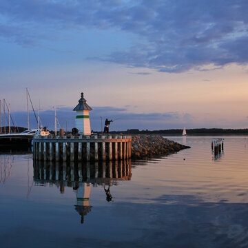 Small lighthouse and sailing boats at sunset in Ebeltoft.