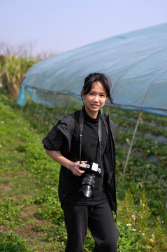 Asian girl practice photography in strawberry field